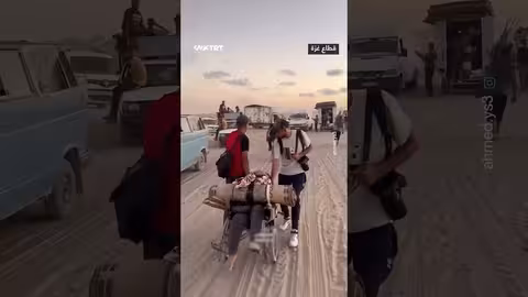 شابان فلسطينيان يساعدان مسنة نازحة في غزة