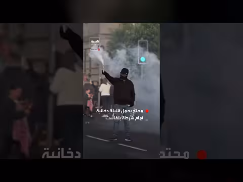 محتج يحمل قنبلة دخانية أمام شرطة بلفاست