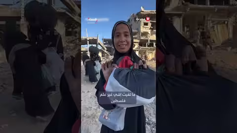 نازحة في خان يونس تتمسك بالعلم الفلسطيني وسط الأنقاض