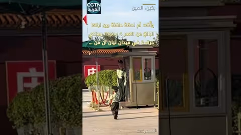 طفل يرتدي زياً عسكرياً يتفاعل مع جندي في ميدان تيان آن من