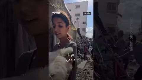 طفلة فلسطينية تواسي كلبتها في غزة خلال القصف