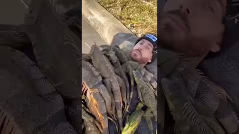 رجل يغطّي جسده بالإغوانا للتدفئة في الطقس البارد